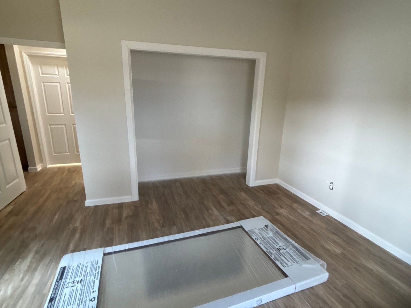 Open closet opening with trimmed frame and new mirrored door still packaged on the floor